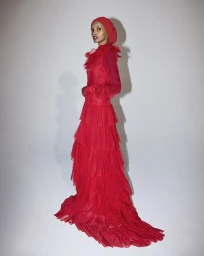 Model Halima Aden wearing a red ruffled gown and matching hijab on a white seamless background for Vogue Arabia.