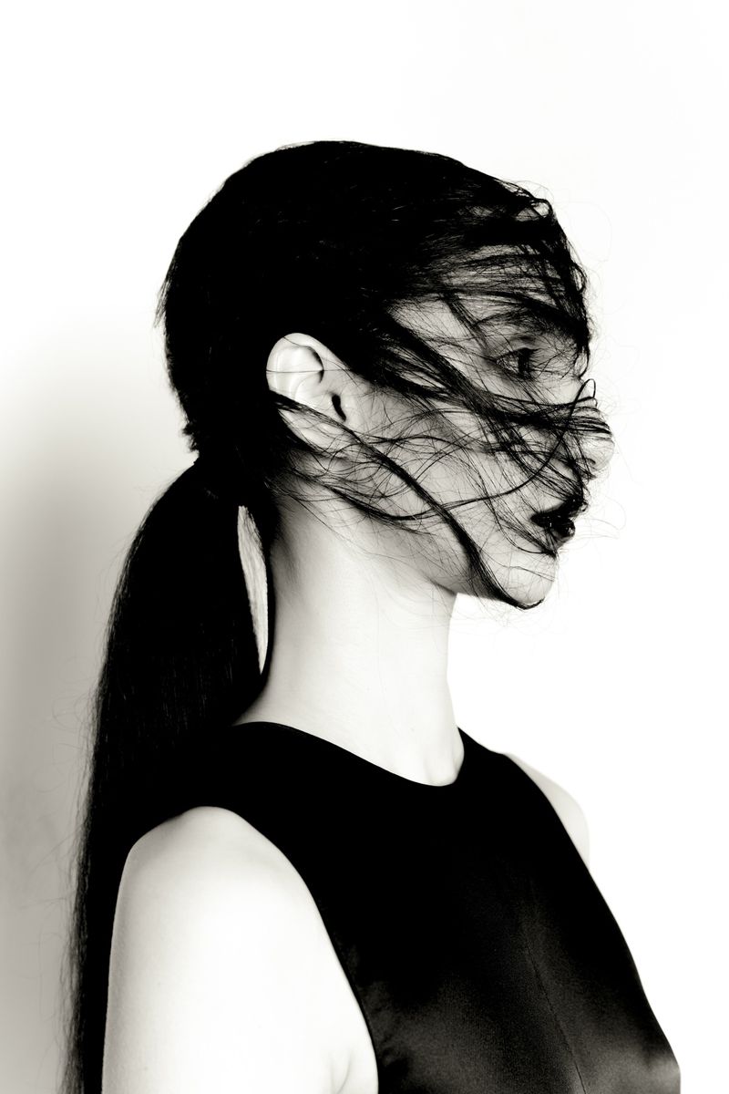 Profile portrait of a woman with dark hair swept across her face against a bright white background for Neo 2 BEA