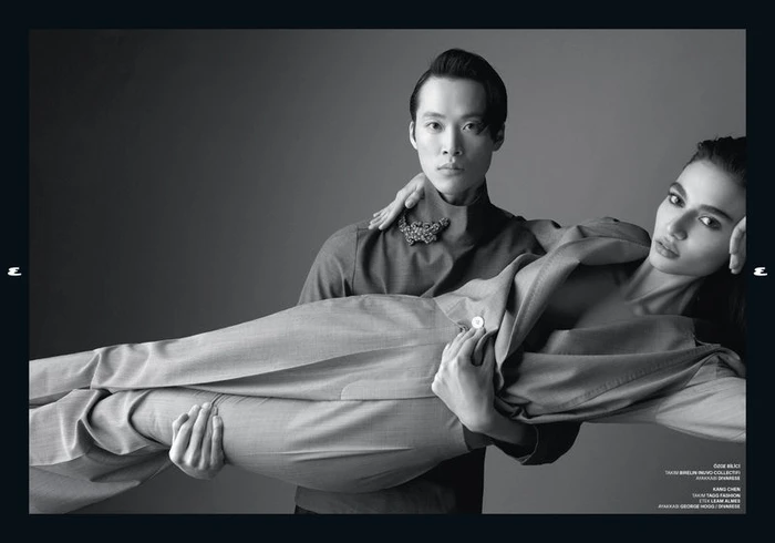 Monochrome studio portrait of a man holding a horizontal woman in a tailored suit for Esquire Turkey by Emre Dogru