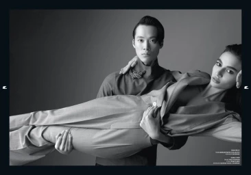 Monochrome studio portrait of a man holding a horizontal woman in a tailored suit for Esquire Turkey by Emre Dogru