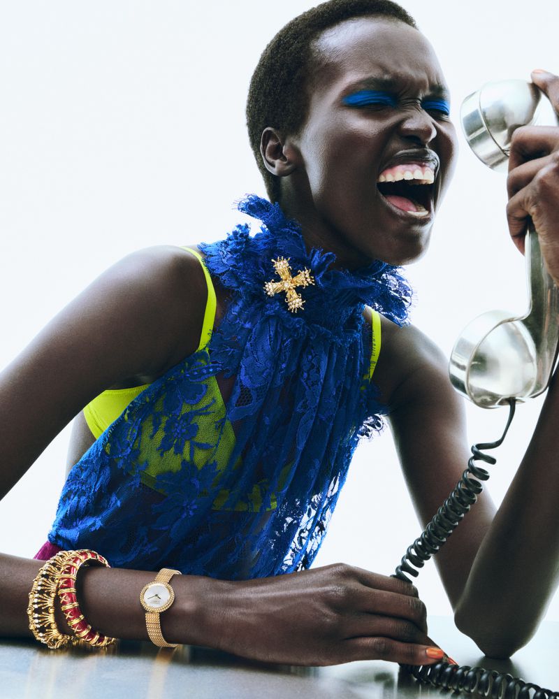 Dramatic portrait of an African-American woman screaming into a retro telephone, showcasing a blue lace top and vibrant makeup.