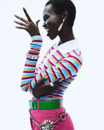 Model Amar Akway wearing a striped polo shirt and pink trousers against a plain white studio background.