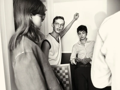 Black and white editorial image featuring three models indoors with a chessboard prop for COAT Magazine Chess Club.