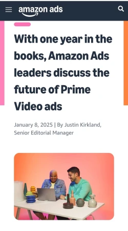Amazon Ads article image. Two men smiling and looking at a laptop on a desk with various objects, against an orange gradient backdrop.