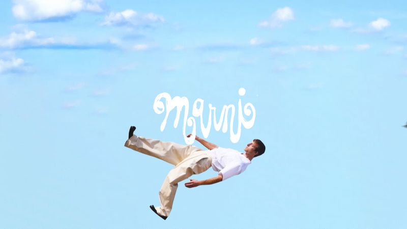 Young man in white shirt and beige pants appears to be floating against a light blue sky with scattered clouds and the text "Marnio".