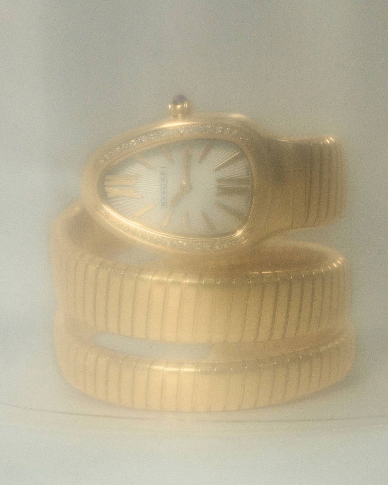 Serpenti Seduttori watch by Bvlgari in gold, featuring a snake-head design with a white dial and diamond bezel, coiled bracelet.