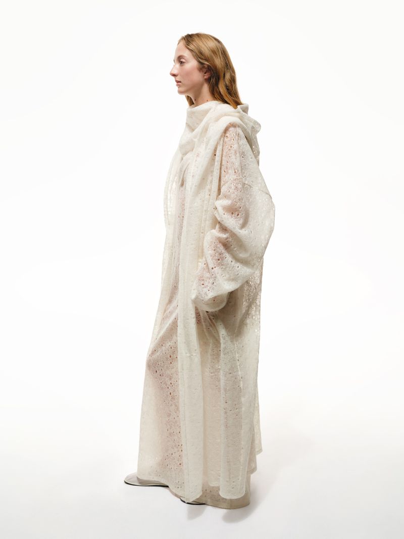 Woman in flowing hooded sheer white dress, side profile, full-length studio shot, clean background, fashion or bridal concept.