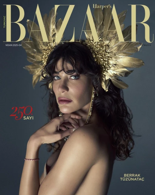Magazine cover featuring Berrak Tüzünataç wearing a gold feather headdress and jewelry, posing against a dark gray backdrop.