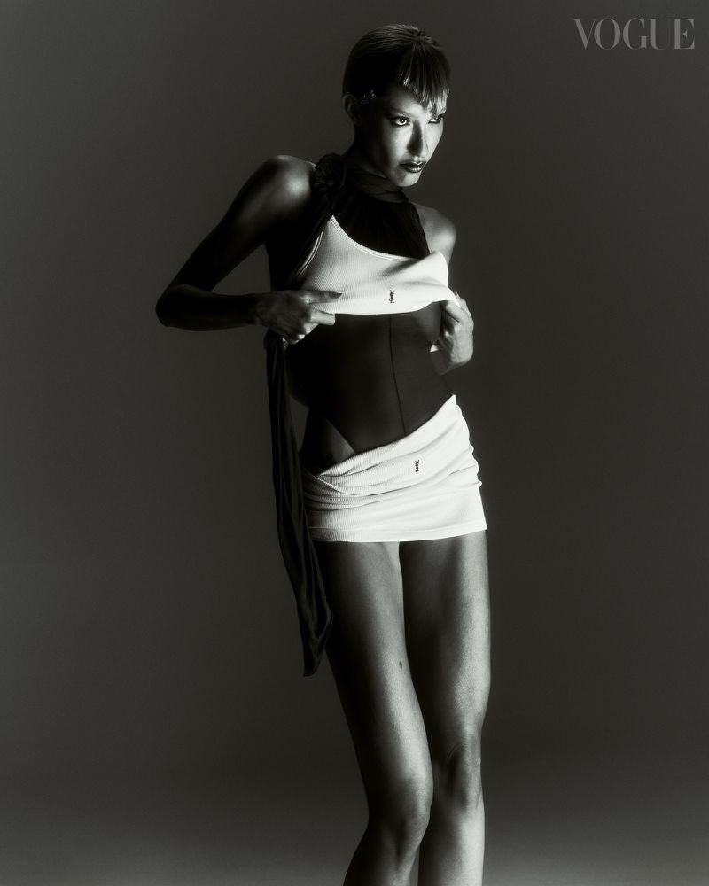 Black and white fashion shot featuring a woman in an abstract bodysuit and wrap in a studio setting for a magazine editorial.