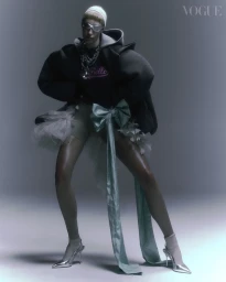 Model in futuristic sunglasses and hooded jacket with tulle tutu and silver heels against grey studio background