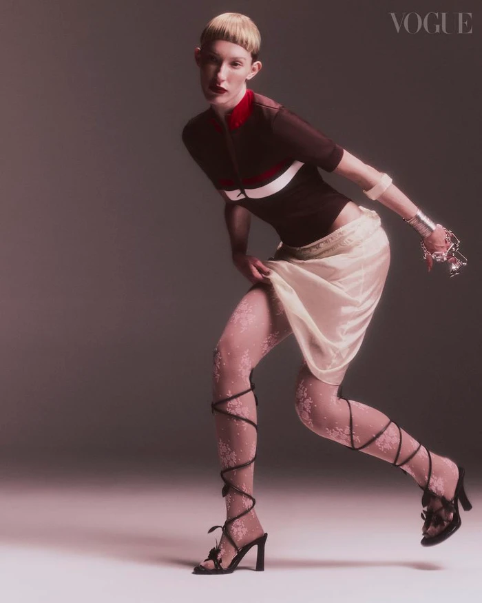 Model in dark top and light skirt posing against a neutral gradient backdrop for Vogue Portugal editorial