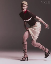 Model in dark top and light skirt posing against a neutral gradient backdrop for Vogue Portugal editorial