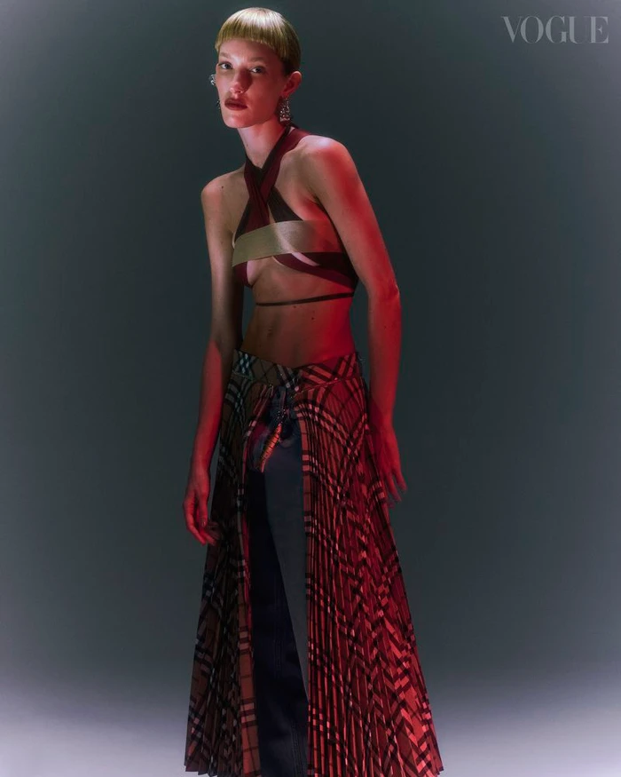 Model in halter top and plaid skirt posing against a dark background for Vogue Portugal