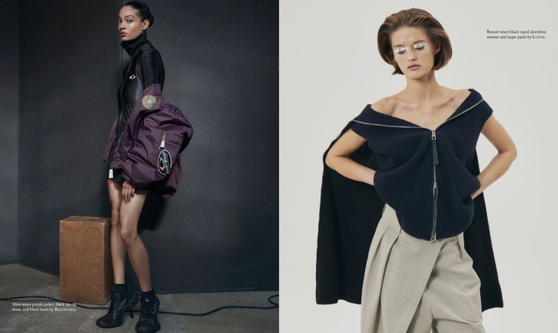 Two fashion models showcase designer outfits in a studio setting. One wears a purple jacket and the other, a caped sleeveless sweater.