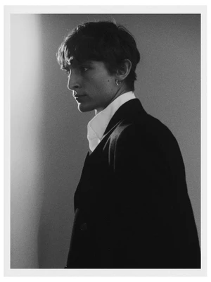 Black and white portrait of male model Vassili Schneider wearing a dark suit jacket and white shirt
