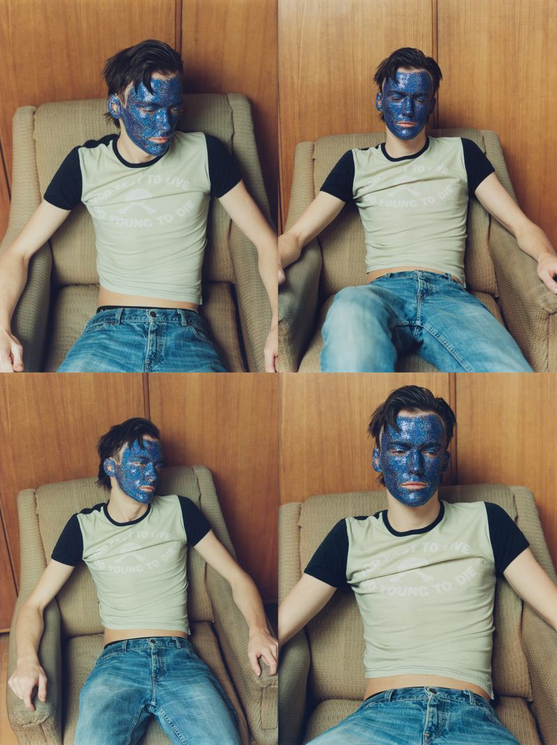 Man with glitter makeup sits in armchair. Four-panel composition shows posed male with blue glitter covering face and body, wearing casual clothing.