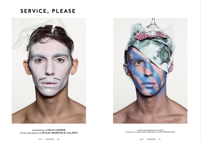 Editorial fashion shot of two young adult males with dramatic makeup and sculptural headwear, presented side by side on a white background.
