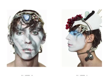 Two portraits of a model with white and metallic face paint, wearing headpieces adorned with pearls, grapes, and household items against a white background.