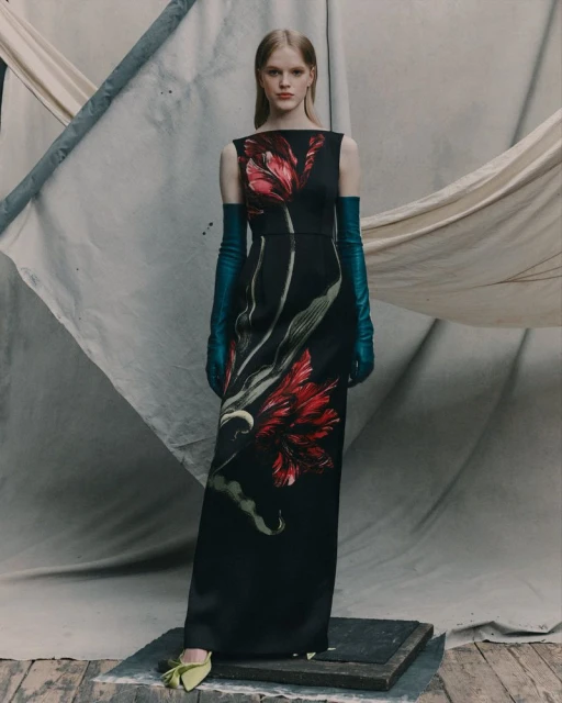 Elegant woman in floral print dress with long blue gloves and light green shoes poses against a neutral backdrop in a fashion editorial.