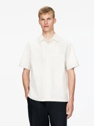 Male model wearing a short-sleeve striped white shirt and dark trousers against a white background for Arket Mens.