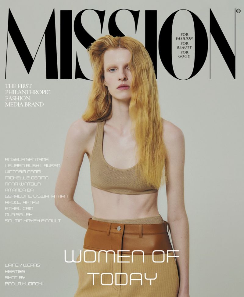 Magazine cover featuring a model with long blonde hair, wearing a tan top and tan and brown pants, against a light background.