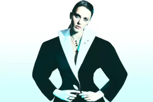 Model wearing structured black blazer with wide white lapels against a plain white studio background for PalaceScope editorial.