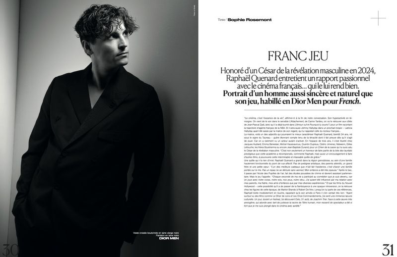 Black and white portrait of a man in a dark double-breasted suit with textured hair, gazing away from the camera in a magazine spread.