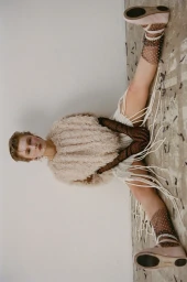 Model seated on the floor wearing a textured cream top, sheer polka-dot socks, and pink shoes for Document Journal SS25.