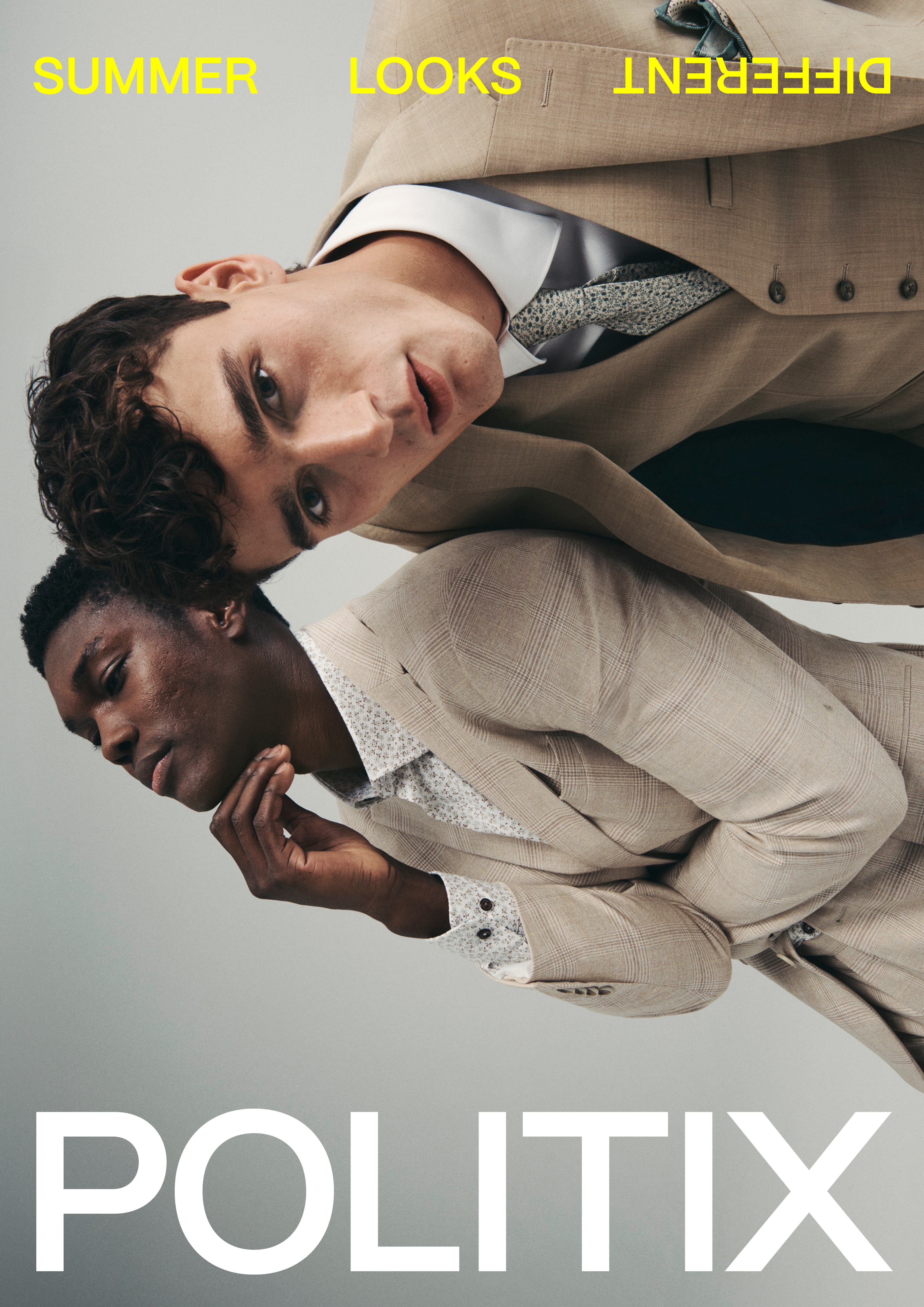 Two men in summer suits pose indoors. One is dark-skinned, and one is light-skinned. The men wear button-down shirts and ties.