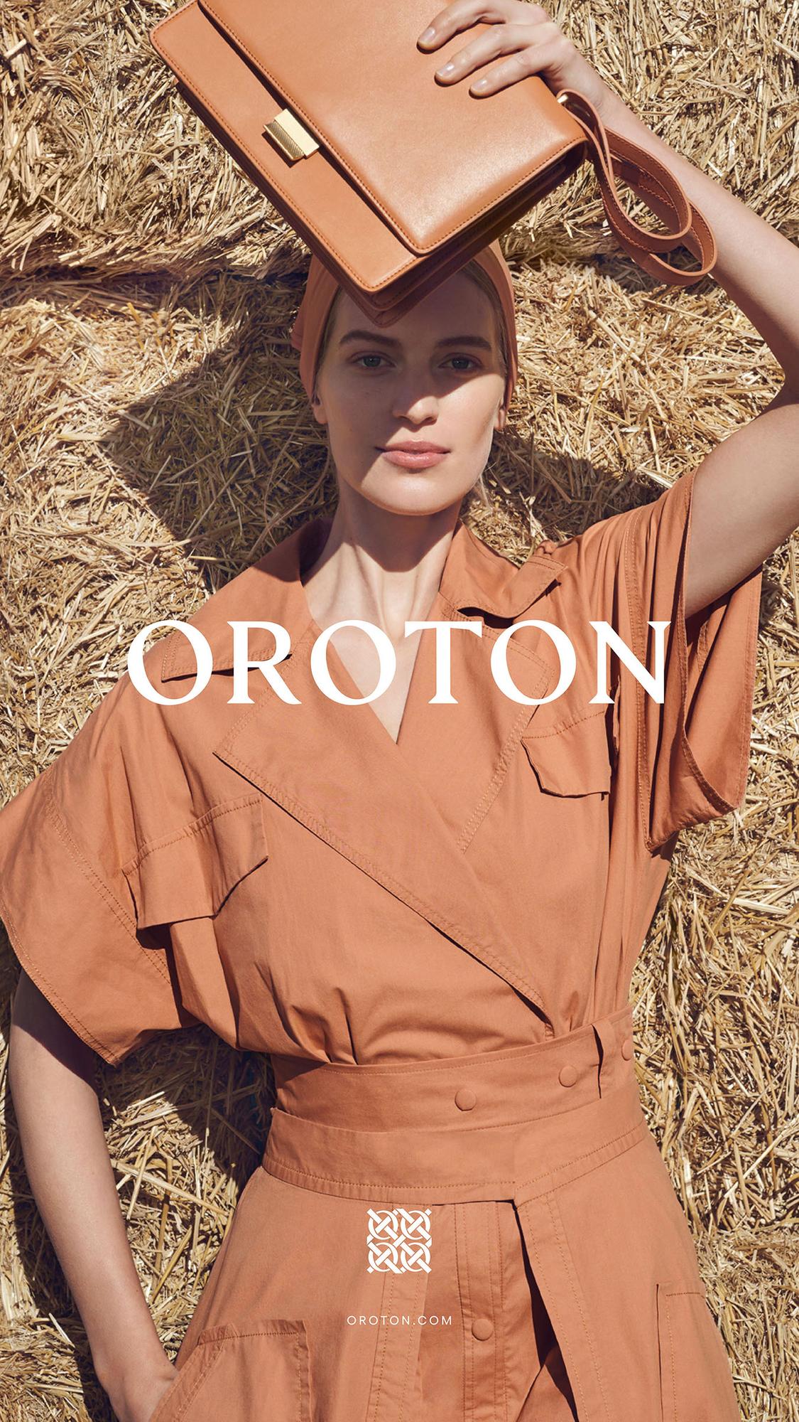 Blonde woman posing with tan leather handbag in field of hay, wearing matching tan dress and headscarf in outdoor editorial fashion shot.