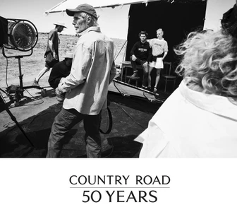 Behind the scenes on a desert photo shoot with crew members and models posing on a set for Country Road 50 Years Campaign.