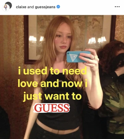 Blonde woman takes a selfie with a phone in front of a mirror, while another person stands out of focus in the background.