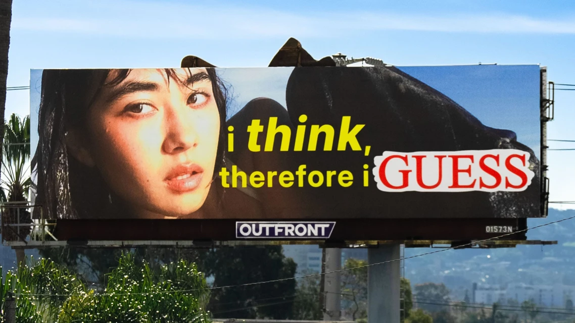 Billboard advertisement with a close up portrait of a woman next to 'I think, therefore I Guess' text with palm trees in the background.