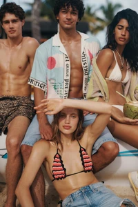 Group of four models posing on a beach wearing summer resort wear and swimwear in a campaign photographed by Simon Lekias