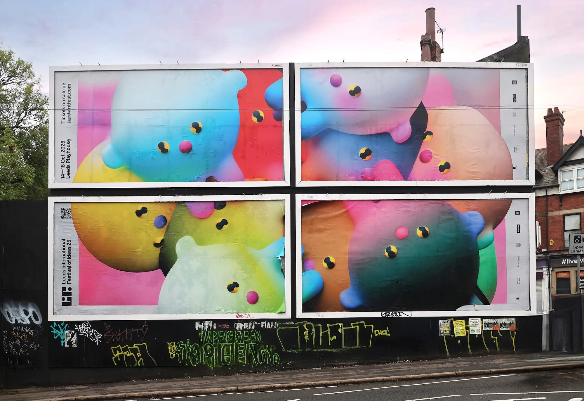 Outdoor billboard featuring an abstract, colorful image. The image displays rounded, blob-like forms in blue, red, yellow, and green hues.