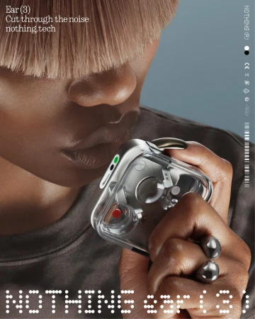 Close-up of a person with light brown hair holding 'Nothing Ear (3)' earbuds, focusing on the tech's design and fashionable presentation.