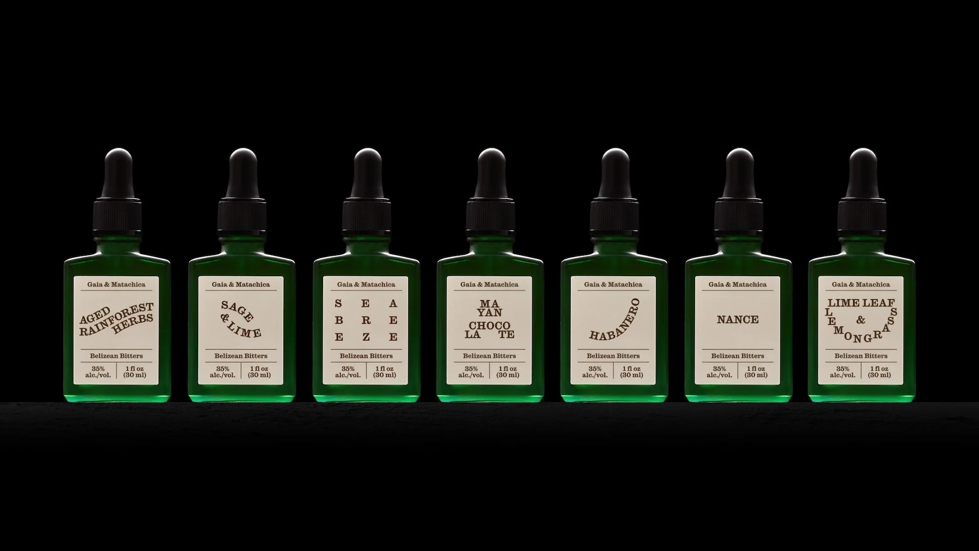 Seven green glass bottles with black droppers, labeled with various flavors of bitters, arranged in a row against a black background.
