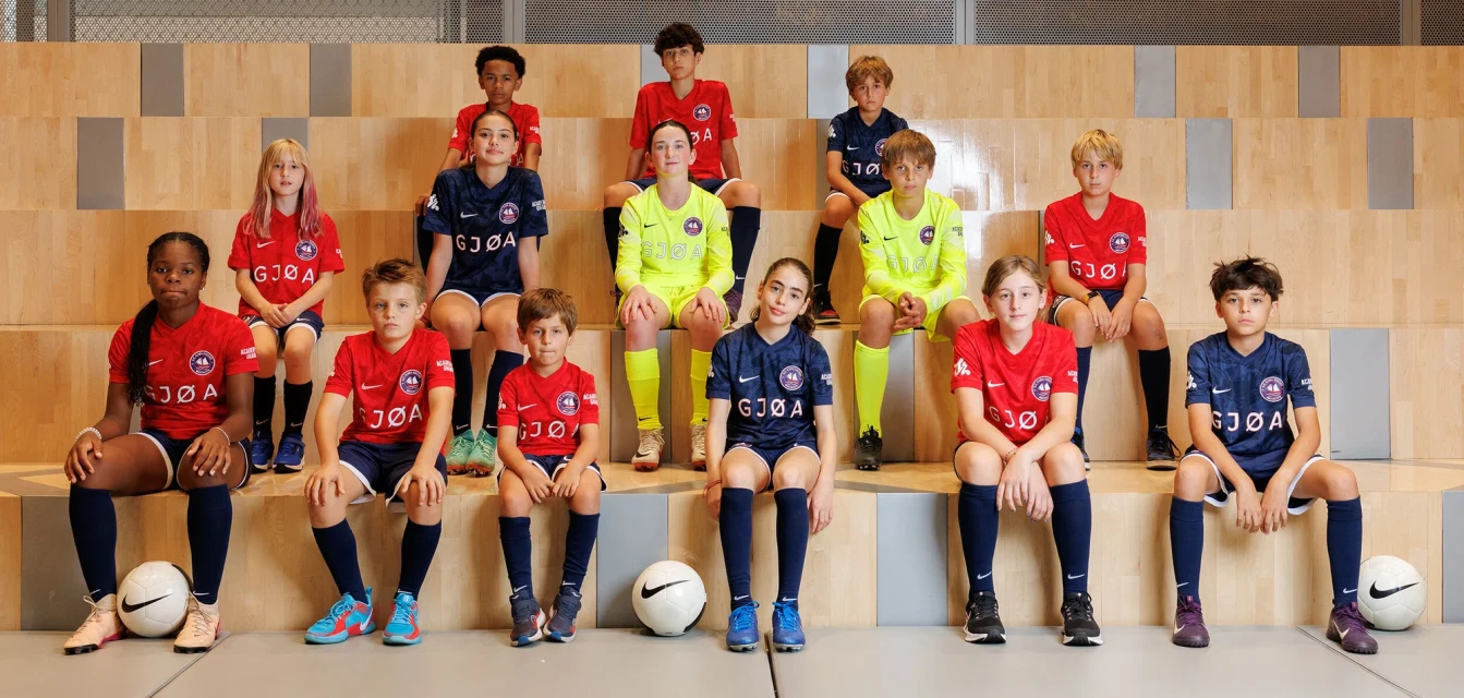 Group of young soccer players in team uniforms sitting on steps. The athletes are wearing matching jerseys and shorts with athletic shoes.