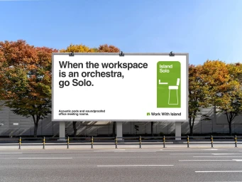 A large billboard advertising Work With Island featuring bold typography and a green graphic next to trees and an empty street.