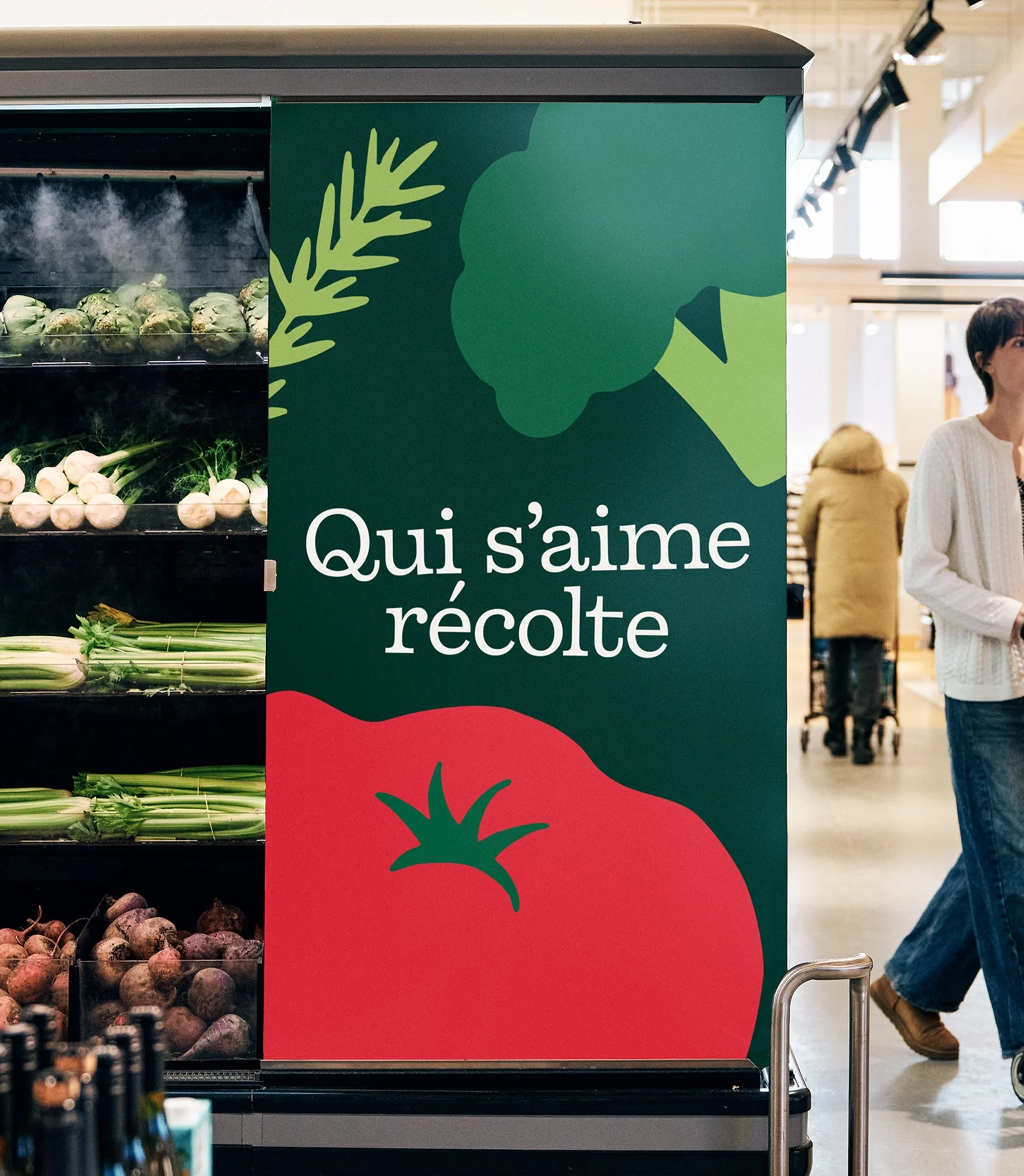Eye-level shot of a grocery store produce section cooler with fresh vegetables, and a promotional sign with illustrated vegetables.