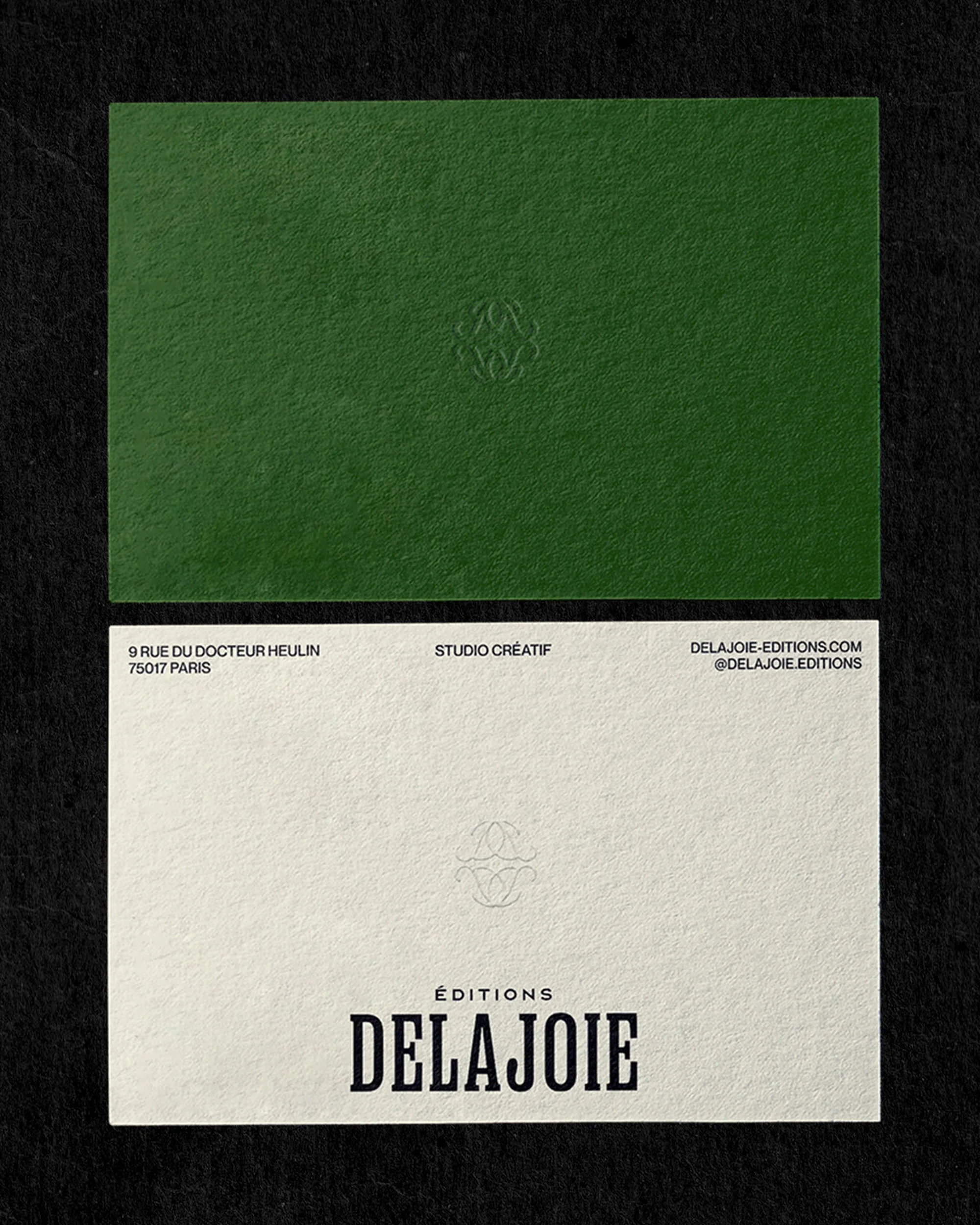 Two business cards, one green and one white, displayed on a black surface, with the text 'DELAJOIE' prominently featured on the white card.