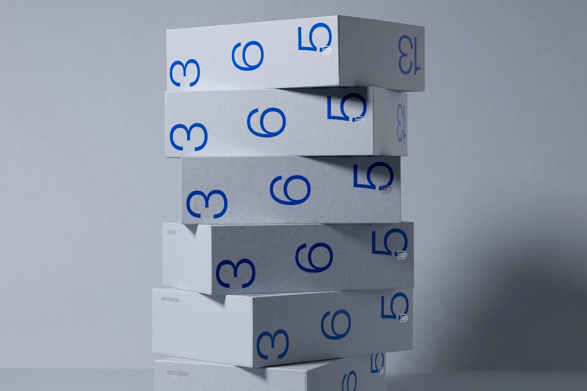 Stack of white product boxes with blue lettering '3', '6', and '13' on a white reflective surface against a solid white background.