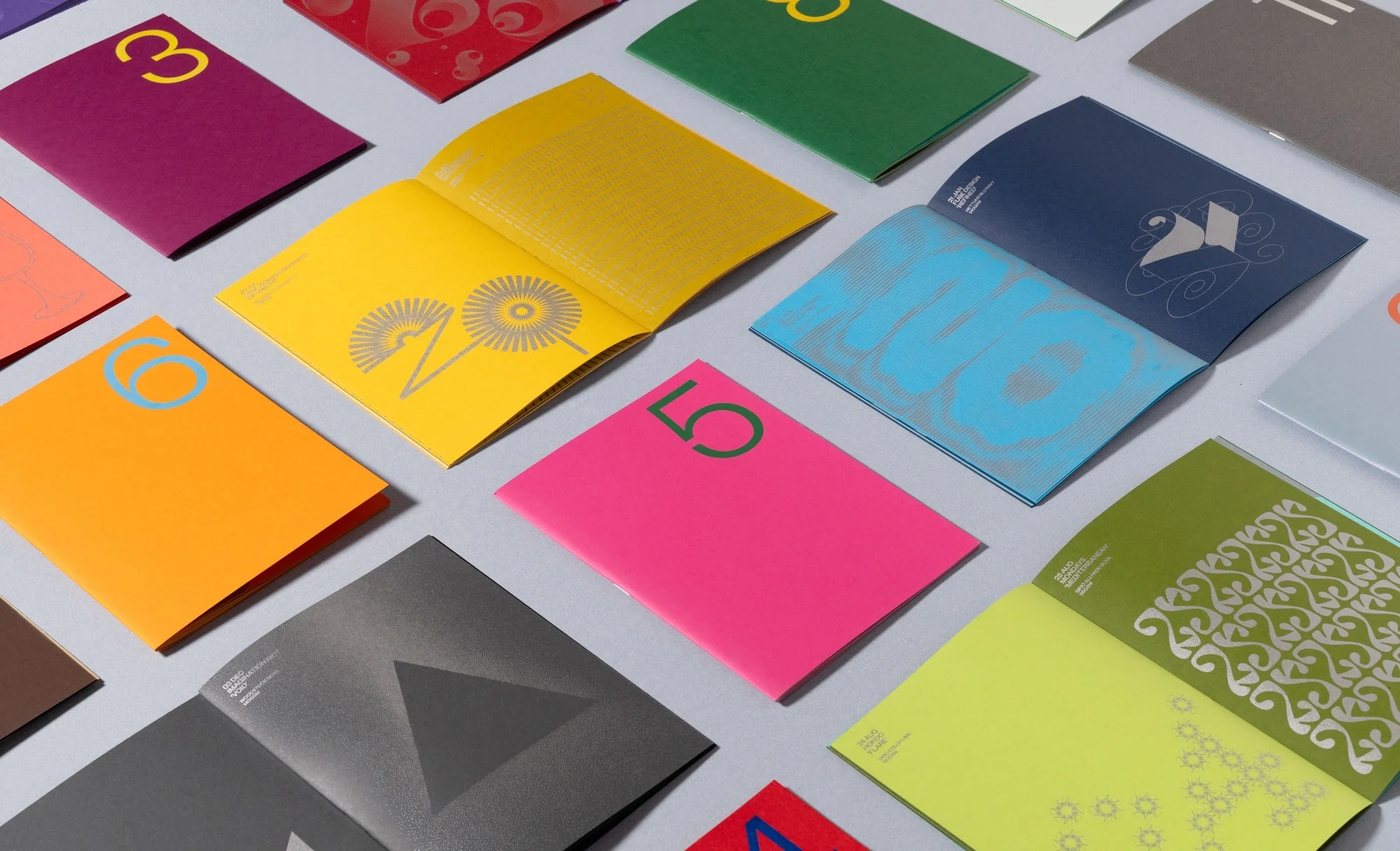 Collection of vibrant, colourful brochures and booklets with bold numeral typography, creating an eye-catching graphic design display.