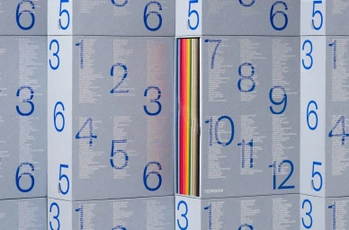Grey paper packaging boxes with large blue numbers and typography containing colourful spines inside