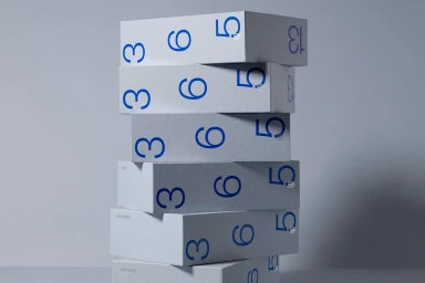 A vertical stack of pale grey custom paper boxes printed with bold blue numbers against a neutral background.