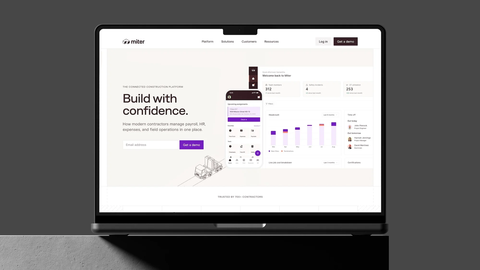 Laptop displays Miter construction platform website with tagline 'Build with confidence' and a user interface featuring graphs and charts.
