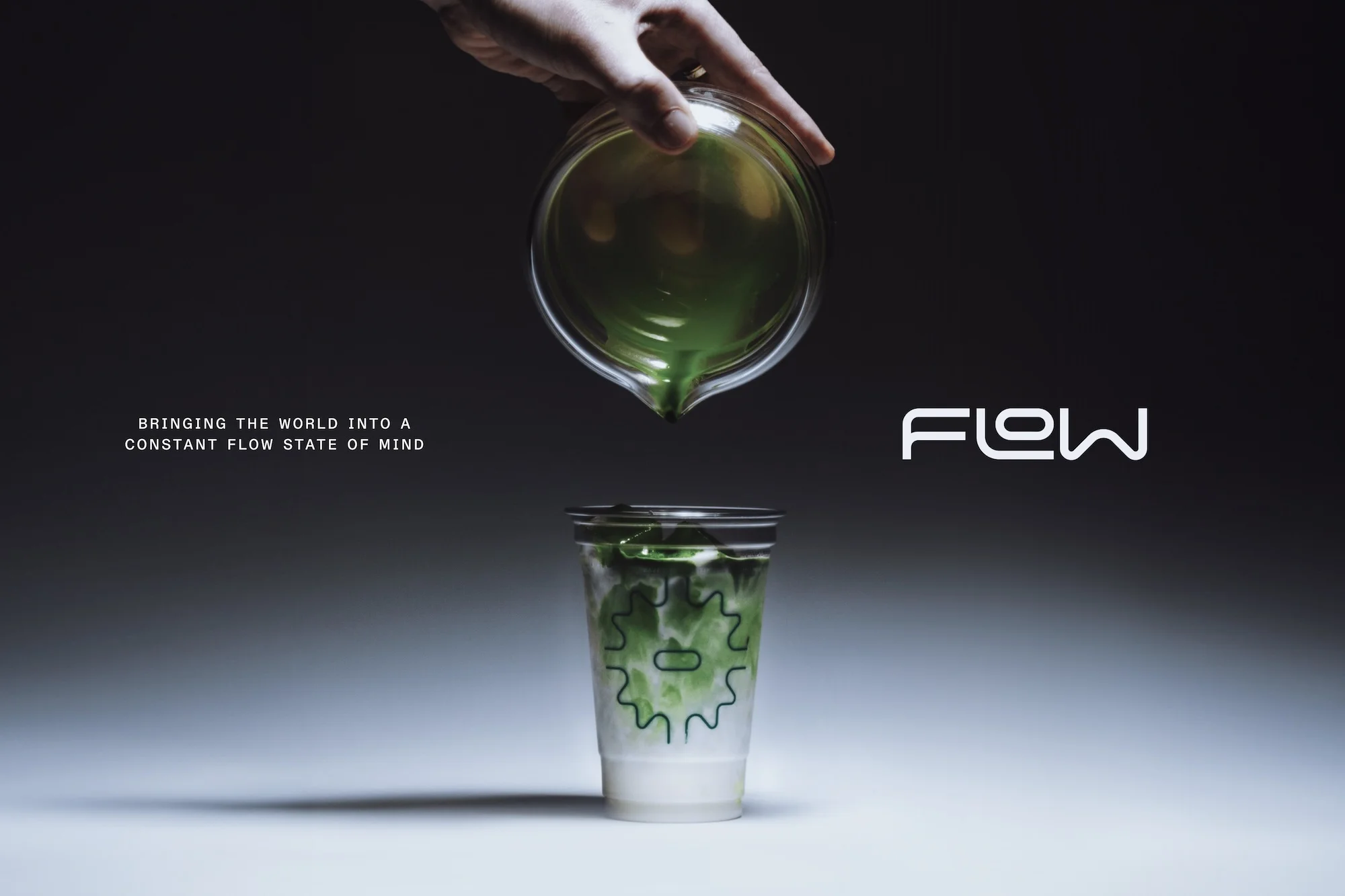Hand pours green liquid from glass beaker into a plastic cup with logo on gradient gray background in studio product shot.