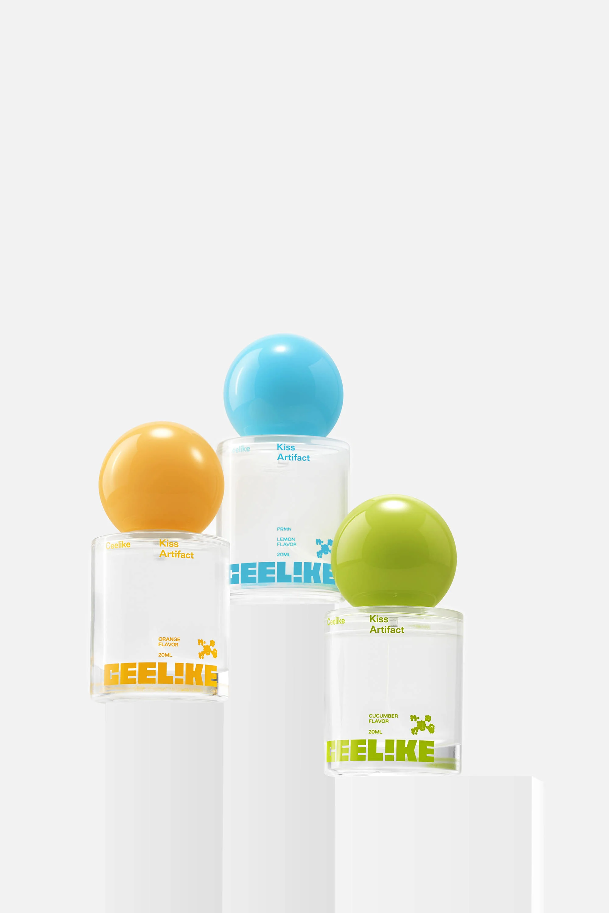 Three perfume bottles with colorful spherical caps arranged on white pedestals against a clean, white background in a studio setting.