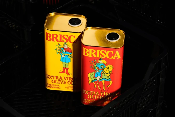 Two colorful olive oil tins, Brisca brand, one yellow with a person illustration and the other red with a horse rider illustration.
