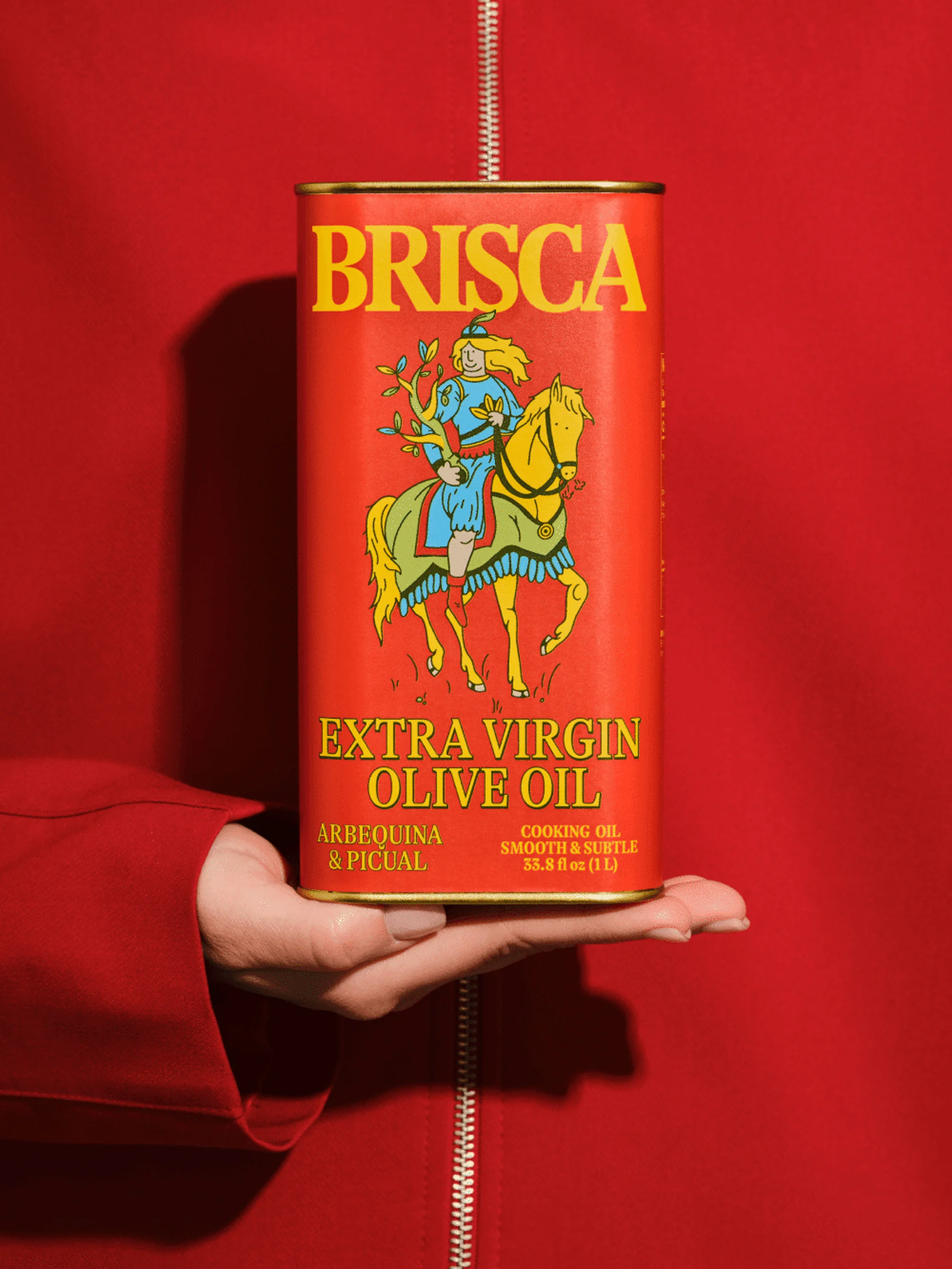 A can of Brisca extra virgin olive oil held in a hand against a red background. The can features an illustration of a knight on horseback.